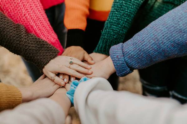 Teambuilding: Hände werden in Mitte zusammen gehalten